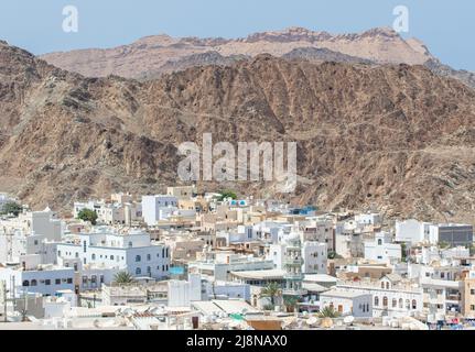 Die Hauptstadt und bevölkerungsreichste Stadt im Oman, Muscat, zeigt erstaunliche Orte, an denen seine weißen Gebäude von beeindruckenden Bergen umgeben sind Stockfoto