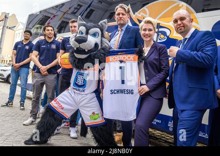 Schwerin, Deutschland. 17.. Mai 2022. Manuela Schwesig (SPD, M), die Ministerpräsidentin von Mecklenburg-Vorpommern, hält ihr neues Trikot mit der Nummer 1 zwischen den Vorstandsmitgliedern Jens Hakanowitz (l) und André Jürgens (r) und den Basketballspielern der Rostock Seawolves. Mit ihrem Eintritt in das Playoff-Finale der 2. Liga ProA, die Mecklenburger Seenplatte hatten letzte Woche ihre erste Beförderung zum deutschen Basketball-Spitzenflug Perfect gemacht. Quelle: Jens Büttner/dpa/Alamy Live News Stockfoto