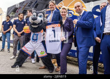 Schwerin, Deutschland. 17.. Mai 2022. Manuela Schwesig (SPD, M), die Ministerpräsidentin von Mecklenburg-Vorpommern, hält ihr neues Trikot mit der Nummer 1 zwischen den Vorstandsmitgliedern Jens Hakanowitz (l) und André Jürgens (r) und den Basketballspielern der Rostock Seawolves. Mit ihrem Eintritt in das Playoff-Finale der 2. Liga ProA, die Mecklenburger Seenplatte hatten letzte Woche ihre erste Beförderung zum deutschen Basketball-Spitzenflug Perfect gemacht. Quelle: Jens Büttner/dpa/Alamy Live News Stockfoto