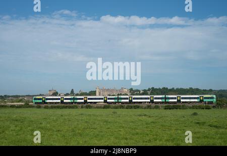 Ein Zug fährt durch die englische Landschaft vor der Stadt Arundel mit ihrem Schloss und der Kathedrale. Der Zug kommt von der Südbahn. Stockfoto