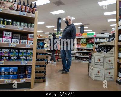 Kirkland, WA USA - ca. März 2022: Ansicht eines älteren Mannes, der in der Alkoholabteilung eines Trader Joe's Lebensmittelladens Bier einkauft. Stockfoto