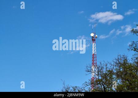 Der Mobilfunkturm ragt über die Bäume, der Telekommunikationsturm. Stockfoto