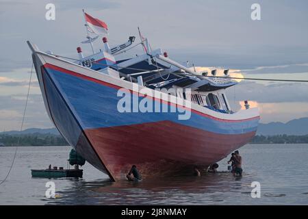 Kendari, Süd-Ost Sulawesi, Indonesien. 17.. Mai 2022. Fischer reinigen das Boot von Austern, die am Rumpf befestigt sind, bevor sie den Rumpf in Kendari lackieren, Dienstag, den 17. Mai 2022.Fischer in Kendari nutzen die ungünstige Wetterlage, um zum Meer zu fahren, indem sie ihr Fischerboot reparieren und warten, Dienstag, den 17. Mai 2022. (Bild: © Andry Denisah/ZUMA Press Wire) Stockfoto