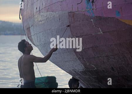 Kendari, Süd-Ost Sulawesi, Indonesien. 17.. Mai 2022. Fischer reinigen das Boot von Austern, die am Rumpf befestigt sind, bevor sie den Rumpf in Kendari lackieren, Dienstag, den 17. Mai 2022.Fischer in Kendari nutzen die ungünstige Wetterlage, um zum Meer zu fahren, indem sie ihr Fischerboot reparieren und warten, Dienstag, den 17. Mai 2022. (Bild: © Andry Denisah/ZUMA Press Wire) Stockfoto