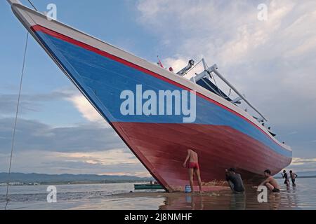 Kendari, Süd-Ost Sulawesi, Indonesien. 17.. Mai 2022. Fischer reinigen das Boot von Austern, die am Rumpf befestigt sind, bevor sie den Rumpf in Kendari lackieren, Dienstag, den 17. Mai 2022.Fischer in Kendari nutzen die ungünstige Wetterlage, um zum Meer zu fahren, indem sie ihr Fischerboot reparieren und warten, Dienstag, den 17. Mai 2022. (Bild: © Andry Denisah/ZUMA Press Wire) Stockfoto