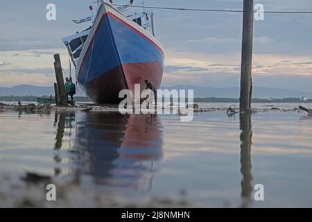 Kendari, Süd-Ost Sulawesi, Indonesien. 17.. Mai 2022. Fischer reinigen das Boot von Austern, die am Rumpf befestigt sind, bevor sie den Rumpf in Kendari lackieren, Dienstag, den 17. Mai 2022.Fischer in Kendari nutzen die ungünstige Wetterlage, um zum Meer zu fahren, indem sie ihr Fischerboot reparieren und warten, Dienstag, den 17. Mai 2022. (Bild: © Andry Denisah/ZUMA Press Wire) Stockfoto