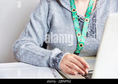 Nicht erkennbare Personen studieren oder arbeiten zu Hause mit einem Notizbuch, das ein Sonnenblumenklederband verwendet, Symbol für Menschen mit unsichtbaren oder versteckten Behinderungen. Stockfoto