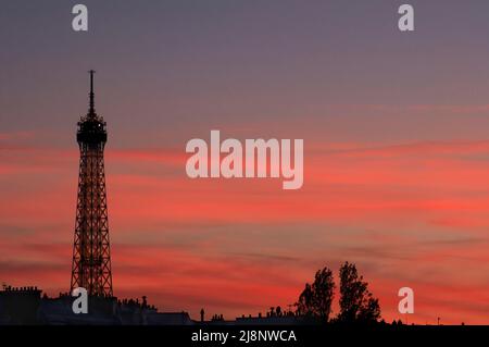 Bei Sonnenuntergang schweben horizontale rosa Wolken hinter dem Eiffelturm. Stockfoto