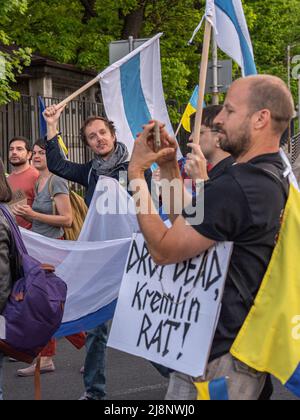 Sofia, Bulgarien - 09. Mai 2022: Ein junger Mann demonstriert die weiß-blau-weiße Flagge der russischen Opposition und geht in einer Menschenmenge auf dem unterstützungsmarsch in der Ukraine Stockfoto