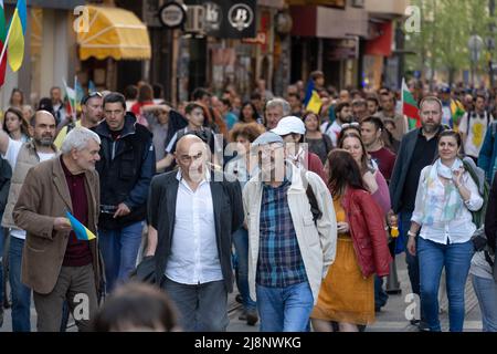 Sofia, Bulgarien - 09. Mai 2022: Drei reife Männer gehen gemeinsam an der überfüllten Straße entlang und diskutieren miteinander freundlich etwas Stockfoto