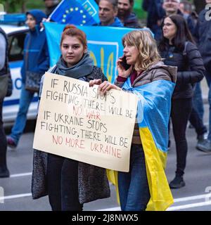 Zwei Frauen mittleren Alters gehen bei einer Demonstration zur Unterstützung der Ukraine mit einem Banner in englischer Sprache zusammen Stockfoto