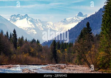 Hoch verschneite Berggipfel mit einem Fluss im Vordergrund Stockfoto