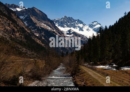 Hoch verschneite Berggipfel mit einem Fluss im Vordergrund Stockfoto