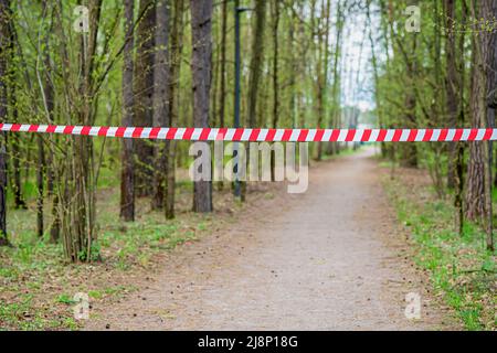 Ziellinie Band im Wald, Sport im Freien. Sport, Country Activity Konzept. Rot-weiß gestreiftes Warnband im Wald Stockfoto