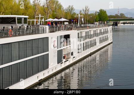 Breisach, Deutschland - April 2022: Menschen auf dem Oberdeck eines Wikinger-Flusskreuzfahrtschiffes, der in Breisach festgemacht ist. Stockfoto