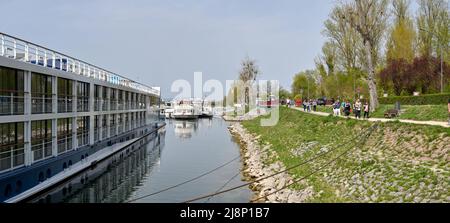 Breisach, Deutschland - April 2022: Panoramablick auf Touristen, die in Breisach am Rhein entlang eines Fußweges an Bord ihres Flusskreuzfahrtschiffes gehen Stockfoto