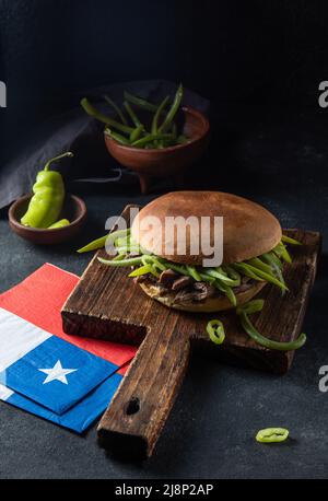 Chilenischer lateinamerikanischer Sandwich-Burger Chacarero mit hochwertigen Rinderschnitten und grünen Bohnen auf schwarzem Hintergrund. Stockfoto