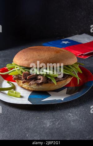 Chilenischer lateinamerikanischer Sandwich-Burger Chacarero mit hochwertigen Rinderschnitten und grünen Bohnen auf schwarzem Hintergrund. Stockfoto