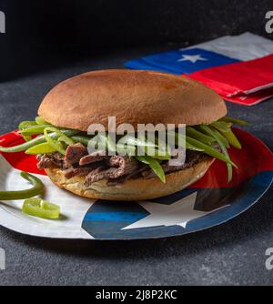 Chilenischer lateinamerikanischer Sandwich-Burger Chacarero mit hochwertigen Rinderschnitten und grünen Bohnen auf schwarzem Hintergrund. Stockfoto