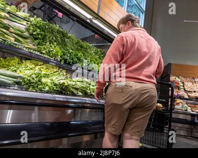 Mill Creek, WA USA - ca. Mai 2022: Schräge Ansicht einer Person, die in der Produktionsabteilung eines Town and Country-Lebensmittelladens Gemüse kauft Stockfoto