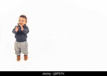 Bezauberndes multirassisches Baby, das Spaß hat, seine Hände klatscht und lacht. Weißer Hintergrund für Studioaufnahmen. Hochwertige Fotos Stockfoto