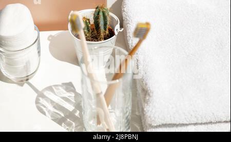 Ecke des Badezimmers. Auf dem Foto Zahnbürsten in einem Glas auf einem Hintergrund aus weißen Baumwollhandtüchern. Stockfoto