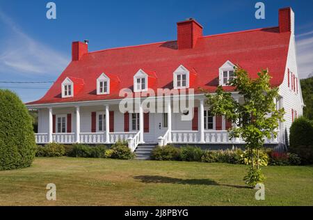 Altes Haus im kanadischen Cottage-Stil aus dem Jahr 1825 mit weißer Holzplankenverkleidung und rot gestrichenen Zedernholzschindeln. Stockfoto