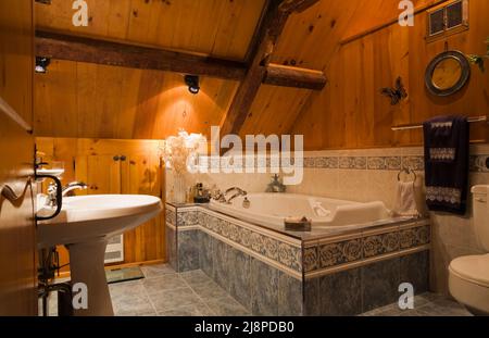 Rustikales schickes Badezimmer mit ummantelter Badewanne im Obergeschoss im alten, ca. 1740 Jahre alten Haus im kanadischen Cottage-Stil. Stockfoto