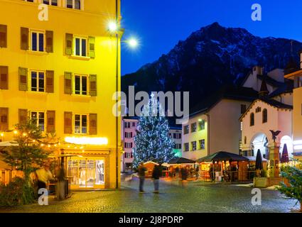 Nachtansicht der Brig Straße mit Weihnachtsbaum im Hintergrund der Alpen, Schweiz Stockfoto