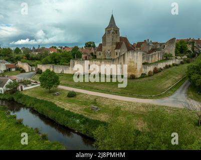 Luftaufnahme von Ainay le Chateau aus dem Osten, kleine mittelalterliche Stadt im Département Allier in Frankreich mit Stadtmauer und Stadttor-Uhrturm bewölktem Himmel Stockfoto