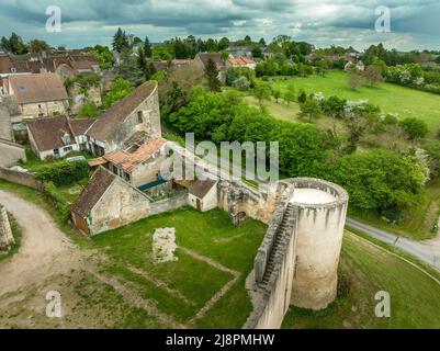 Luftaufnahme von Ainay le Chateau aus dem Osten, kleine mittelalterliche Stadt im Département Allier in Frankreich mit Stadtmauer und Stadttor-Uhrturm bewölktem Himmel Stockfoto