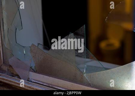 Zerbrochenes Glas bricht und tritt in das Fenster des Schlafzimmers ein. Zerbrochene und zerbrochene Glasscheibe. Stockfoto