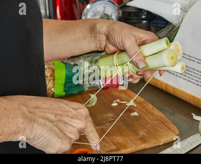 Der Koch bindet Lauch mit einem Seil an, um das Gericht zuzubereiten. Stockfoto