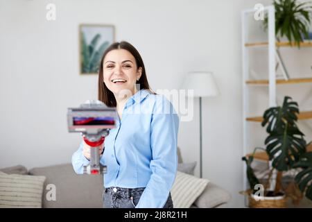 Frau putzt Couch mit Staubsauger zu Hause Stockfoto