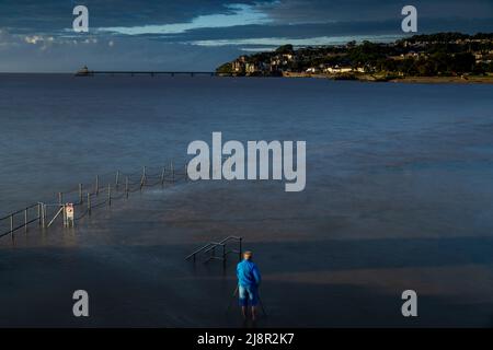 Clevedon Marine Lake, Großbritannien. 17.. Mai 2022. Ein Fotograf, der am Marine Lake fotografiert, während die steigende Flut während der Flut in Somerset die Meeresmauer überflutet Credit: steven paston/Alamy Live News Stockfoto