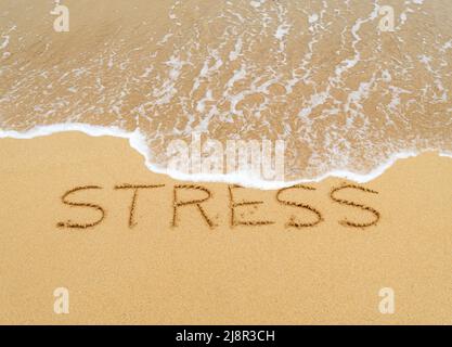 Konzeptbild - um den Stress abzuwaschen, indem man einen Urlaub macht, während die Wellen an einem Sandstrand das Wort „Stress“, das in Sand geschrieben ist, wegspülen. Stockfoto