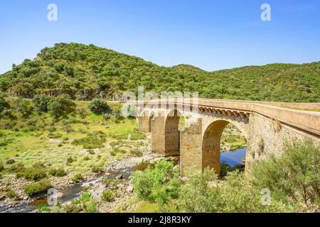 Eine alte Bogenbrücke überspannt den Fluss Salor in Extremadura, Spanien Stockfoto