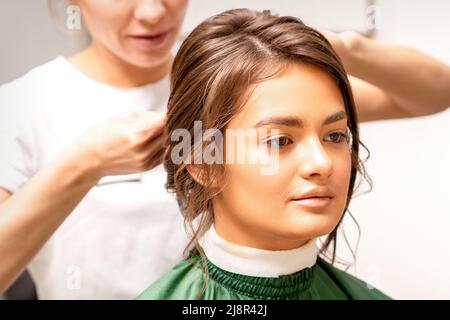 Hairstyling Braut. Eine Friseurin macht in einem Schönheitssalon Stylinghaare für die schöne junge kaukasische Frau Stockfoto