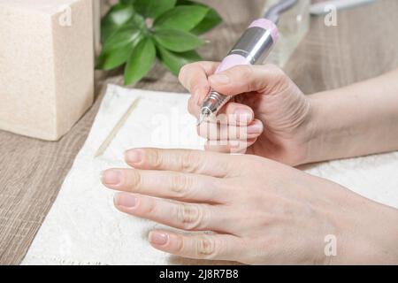 Manikuristin Frau verarbeitet Nägel und Nagelhaut, oder entfernt Nagellack, mit einer Maniküre Maschine, verwenden Sie elektrische Nagelfeile Bohrer im Schönheitssalon.Hardware Stockfoto