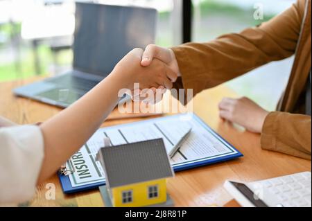 Hausversicherungsmakler oder Immobilienmakler schütteln Hand mit dem neuen Eigentümer im Büro. Wohn-, einen Deal und Vertrag Konzept. Cropped im Stockfoto