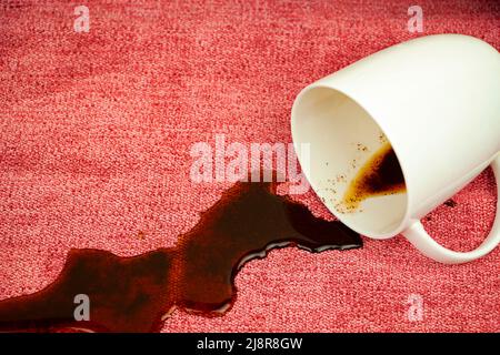 Kaffeefleck auf hellem Stoff, Tischdecke, Sofa. Waschen, Reinigung des Stoffes. Hochwertige Stoffe. Wasserabweisende Imprägnierung. Stockfoto