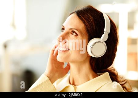 Nahaufnahme einer charmanten jungen kaukasischen Frau mit kabellosen Kopfhörern, die den perfekten Klang ihrer Lieblingsmusik genießen kann Stockfoto