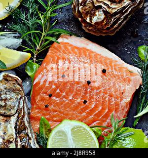 Frisches Fischsteak mit rotem Lachs (Forelle), frischen Austern, Kräutern, Zitrone und Limette. Rohe frische Meeresfrüchte flach, Zitrusfrüchte und Gewürze auf dunklem Hintergrund. Stockfoto