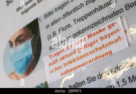 München, Deutschland. 18.. Mai 2022. Auf einem Schild im Landgericht ist ein Aufkleber mit der Aufschrift „Maske tragen gemäß der aktuell gültigen bayerischen Infektionsschutzmassnahmenverordnung“ zu sehen. Kredit: Peter Kneffel/dpa/Alamy Live Nachrichten Stockfoto