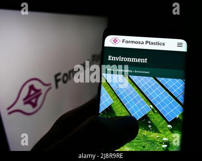 Person, die Mobiltelefon mit der Webseite des taiwanesischen Unternehmens Formosa Plastics Corporation auf dem Bildschirm mit Logo hält. Konzentrieren Sie sich auf die Mitte des Telefondisplays. Stockfoto