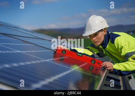 Eine Ingenieurin installiert eine Photovoltaik-Solaranlage auf dem Dach, alternative Energiekonzept. Stockfoto