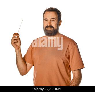 Bärtiger Mann, der Antigen-Test mit unangenehmem Ausdruck durchführt. Auf weißem isoliertem Hintergrund für Werbung. Unbequem beim Abnehmen des Tests. Stockfoto