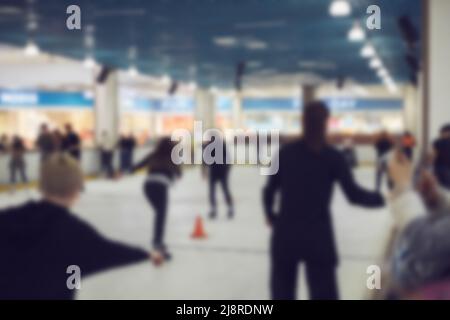 Die Menschen laufen auf einer großen Eisbahn in einem Einkaufszentrum. Unschärfes Bild Stockfoto