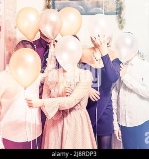Eine Familie versteckt ihre Gesichter hinter Ballons. Fröhliches Urlaubsfoto. Stockfoto
