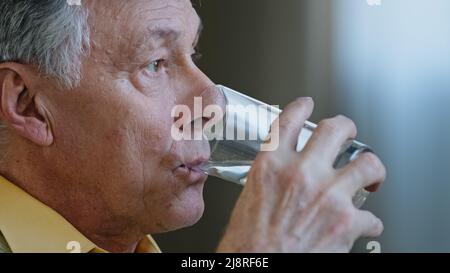 Nahaufnahme ältere ältere ältere kaukasische Mann wegschauen Denken halten Glas sauberes stilles Wasser Getränke H2O Gesundheit Pflege gesunde Gewohnheiten Großvater dr Stockfoto